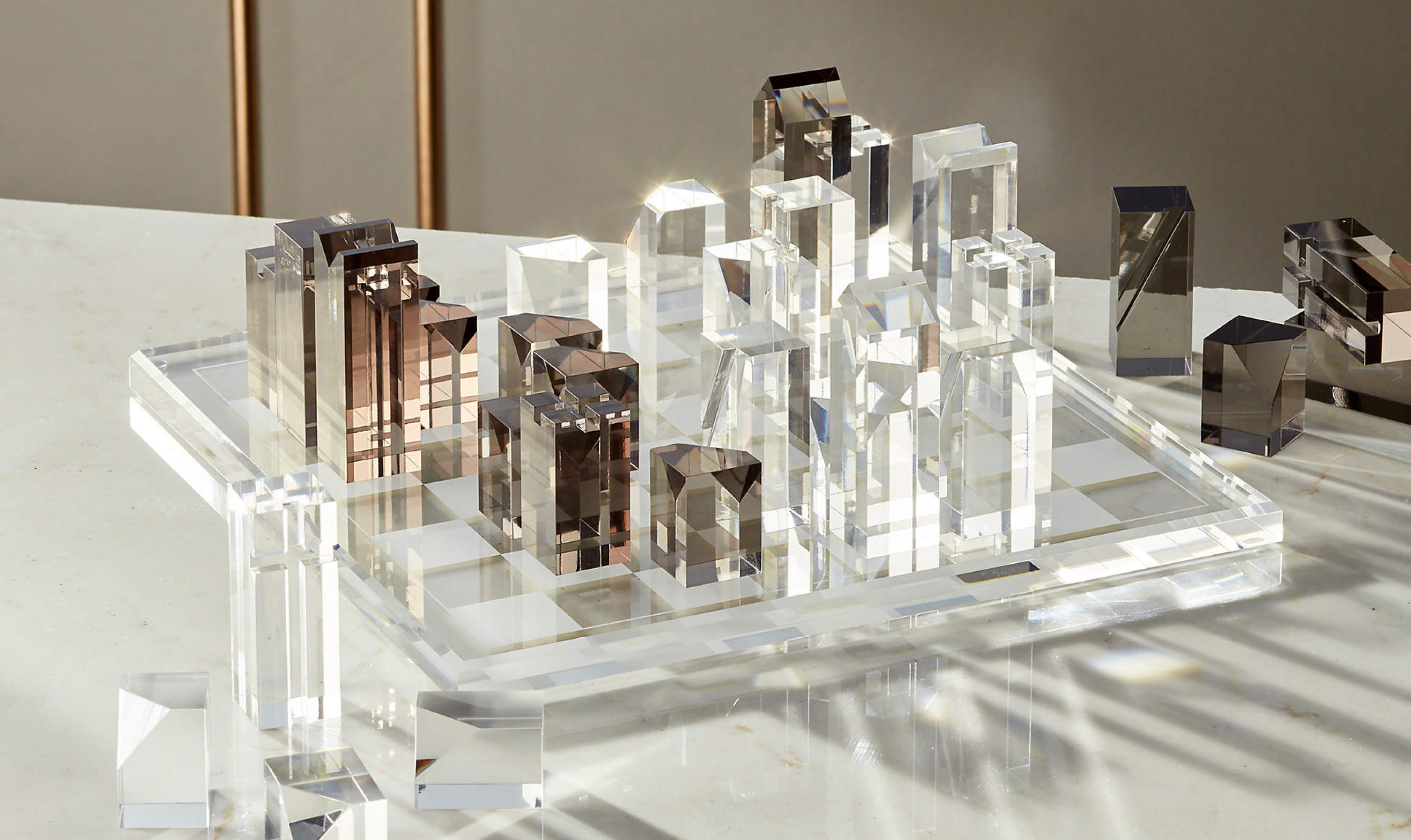 Acrylic light and dark geometric chess pieces on transparent game board.